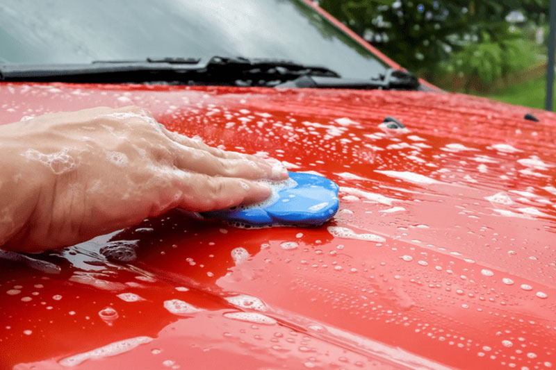 A clay bar for car detailing being used on a red sports car.